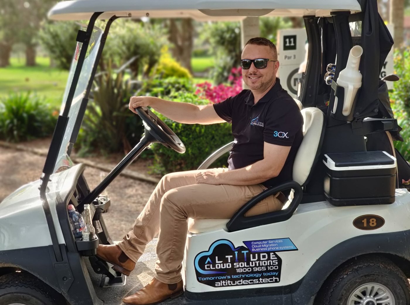 ACS team member in an Altitude Cloud Solutions branded golf cart at a local golf club