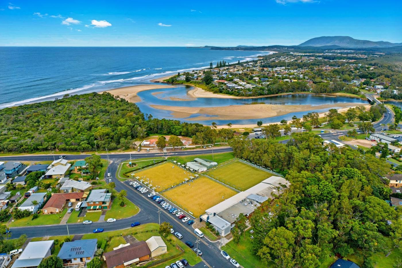 Aerial view of Club Lake Cathie and its bowling greens, with the Lake Cathie inlet and beach behind
